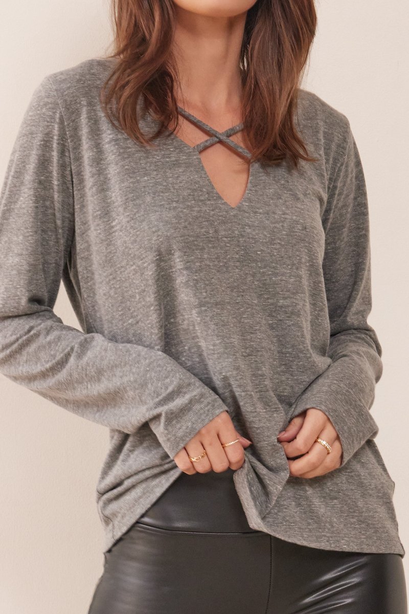 close up of long sleeve gray top with criss cross detailing on chest