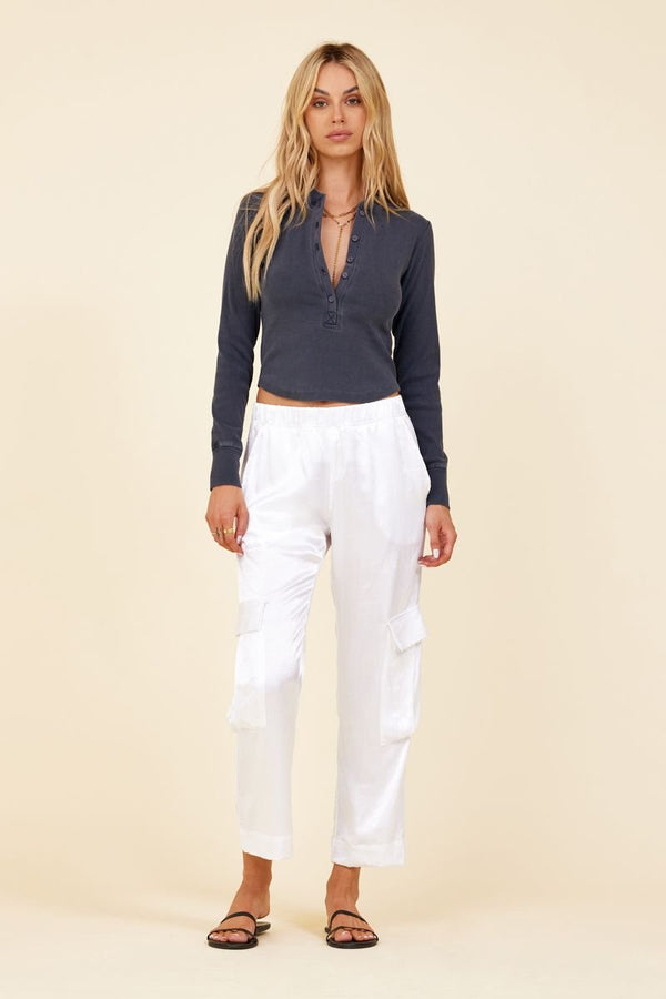full body of a woman in white cargo style pants with a long crop henley