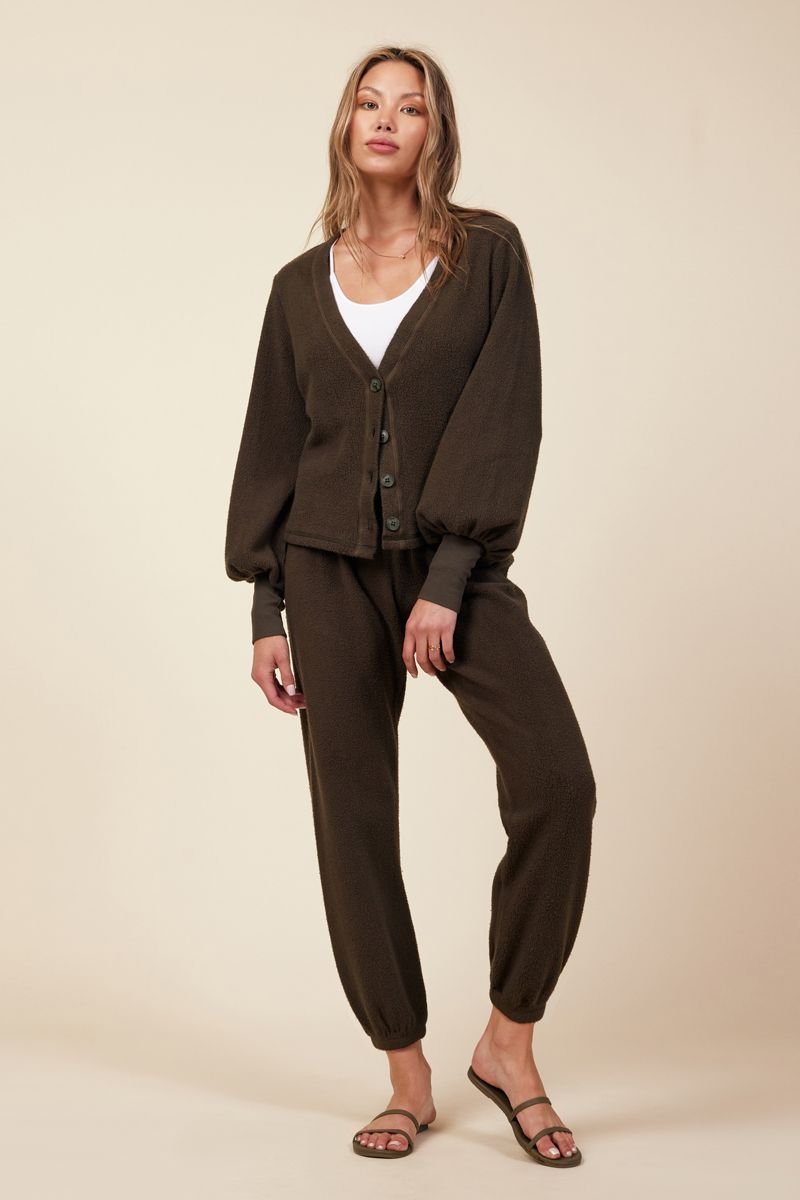 woman standing in dark green loungewear set with a pant and button up cardigan