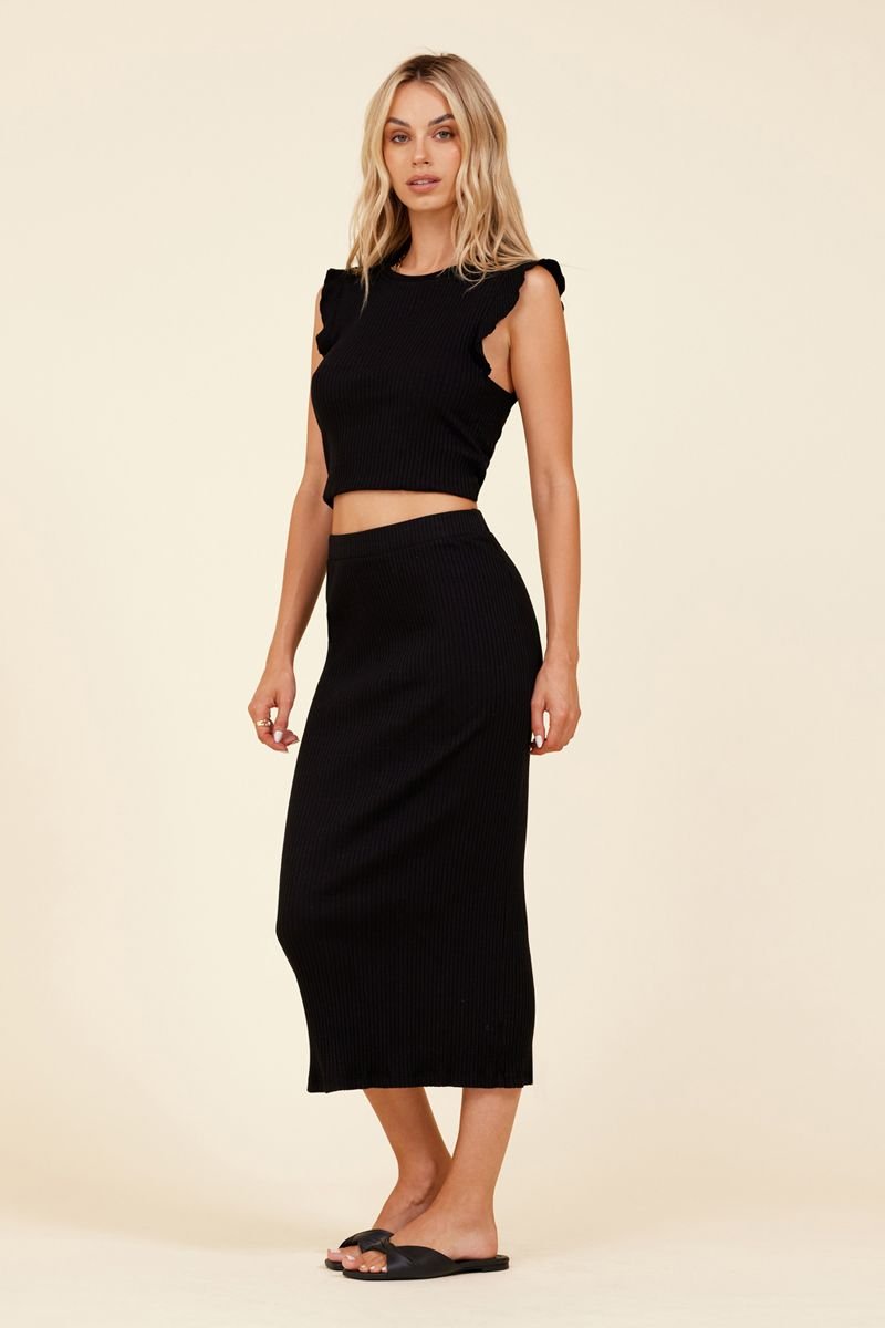 full body of woman standing in black ribbed skirt and crop ruffle shirt